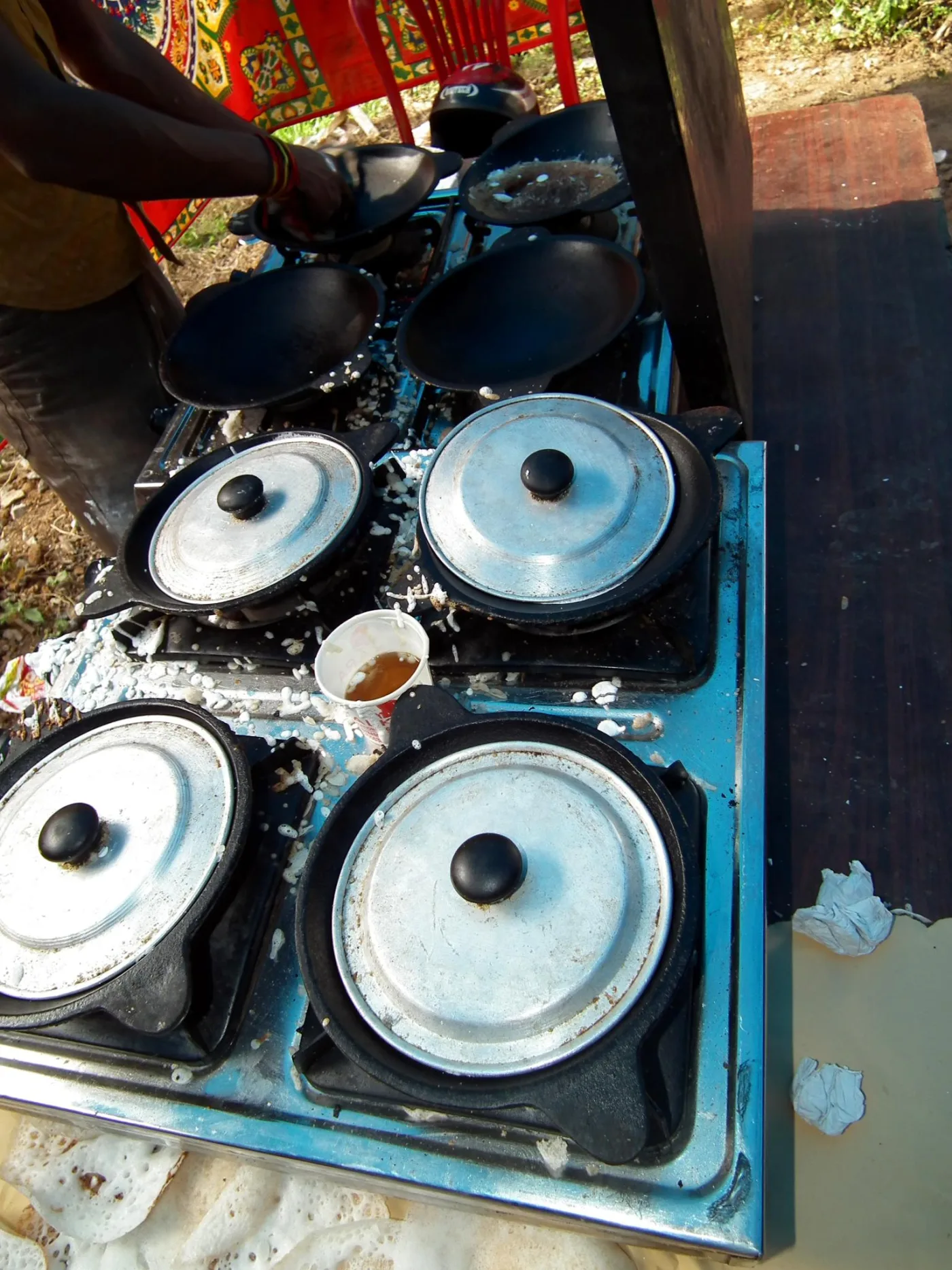 Appams cooking in appachattis on a hotel stove.