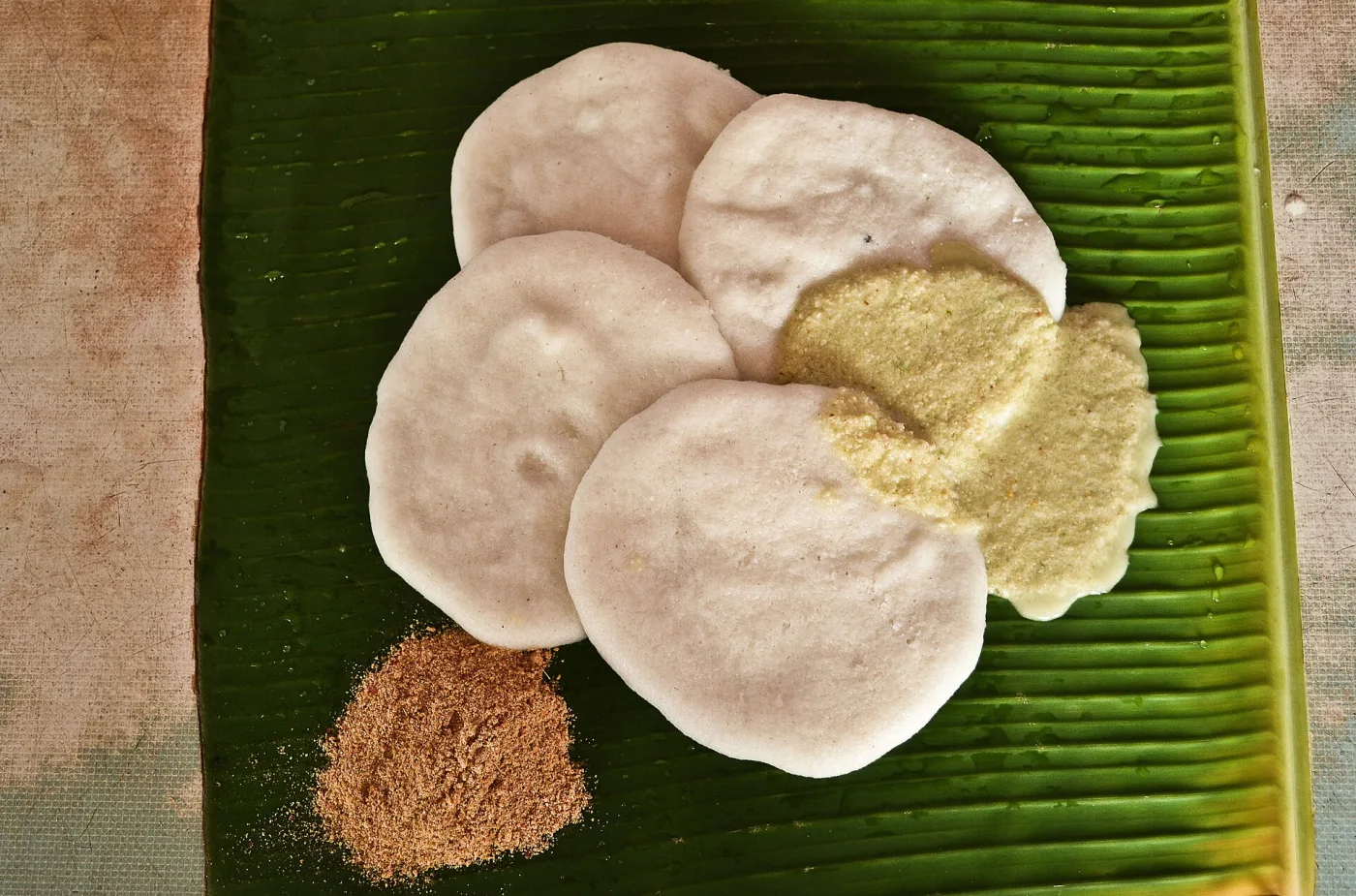 Idli on a banana leaf with coconut chutney and podi.